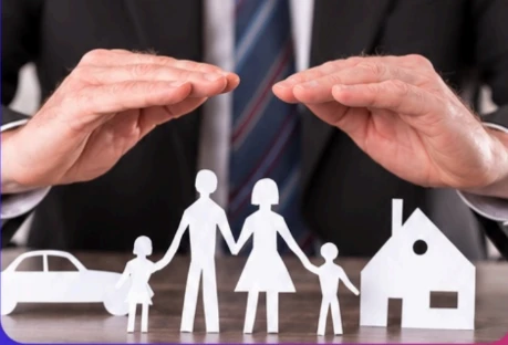 Paper cut-out family, car and house sheltered by two hands